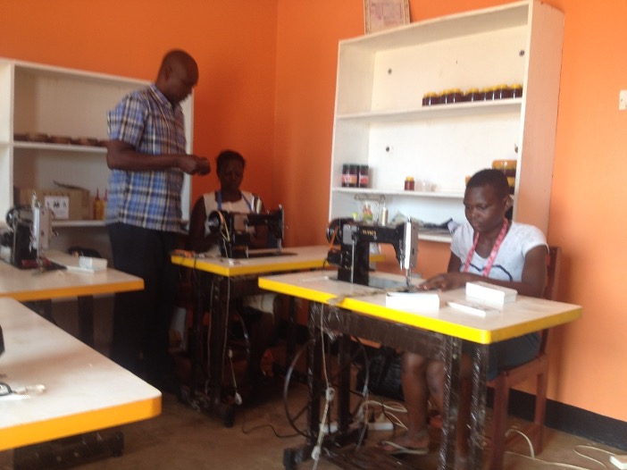 Trainer supervising the women on bee suit making.